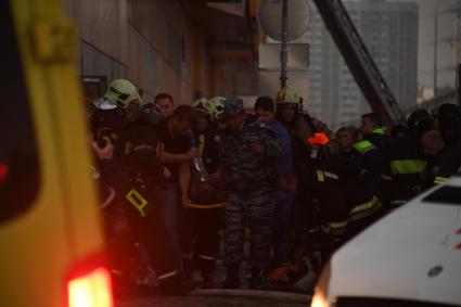 Москва. Сотрудники скорой помощи и ОМОНа эвакуируют пострадавшего с места пожара в здании торгового центра `РИО`на Дмитровском шоссе