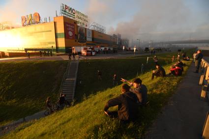 Москва.  Прохожие наблюдают за тушением пожара  в здании торгового центра `РИО` на Дмитровском шоссе.