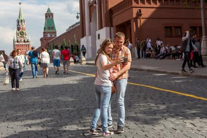 Москва.  Молодые люди делают селфи на Красной площади.