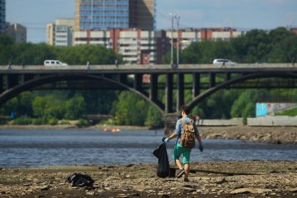 Екатеринбург. Волонтеры собирают мусор с берегов городского пруда обмелевших из-за сброса воды