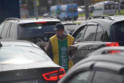 Москва.  Мужчина раздает газеты  на проезжей части дороги.