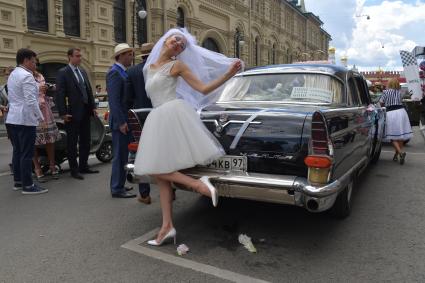 Москва.  Девушка в платье невесты рядом с автомобилем `Чайка`перед  стартом  ГУМ-авторалли Gorkyclassic-2017 возле ГУМа.