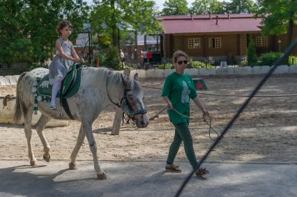 Санкт-Петербург. Девочка катается на лошади в Ленинградском  зоопарке.