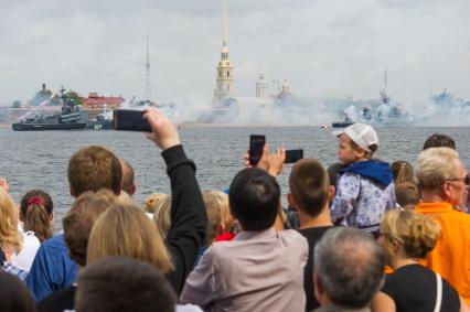 Санкт-Петербург.  Зрители на набережной  фотографируют артиллерийский салют у стен Петропавловской крепости  во время  главного военно-морского  парада  в честь празднования Дня Военно-Морского Флота России.