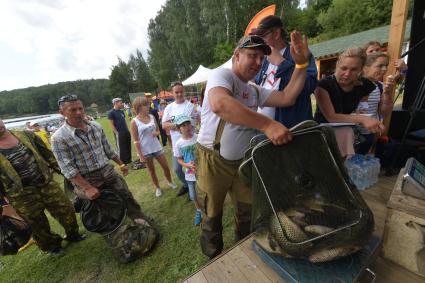 Московская область, д. Мисайлово.  Мужчина взвешивает улов на фестивале семейной рыбалки с радио `Комсомольская правда` в парке рыбалки и отдыха `Лагуна`.