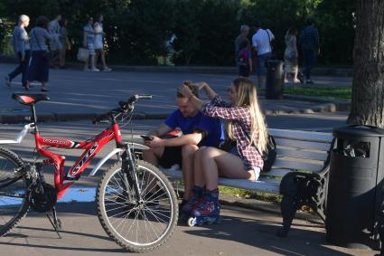 Москва. Молодые люди отдыхают на скамейкев парке Горького.