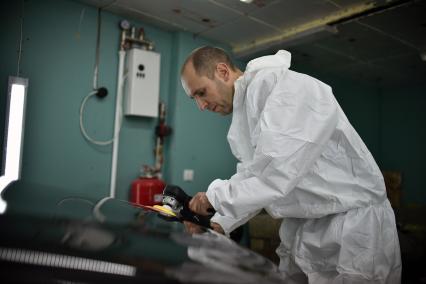 Новосибирск. Сотрудник автосервиса полирует кузов автомобиля.