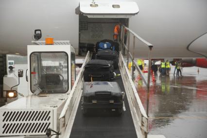 Санкт-Петербург. Загрузка багажа пассажиров в самолет Bombardier CS300 авиакомпании airBaltic в аэропорту `Пулково`.