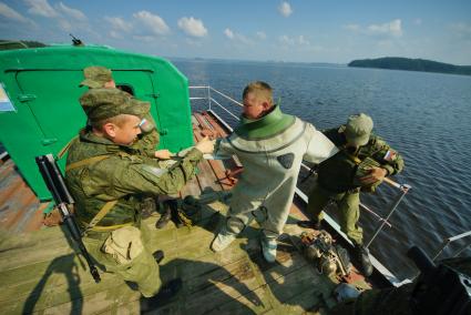 Свердловская область. Военнослужащие помогоют экипироваться водолазу во время тактико-специальных учений соединений железнодорожных войск ЦВО (центральный военный округ) по наведению понтонного моста