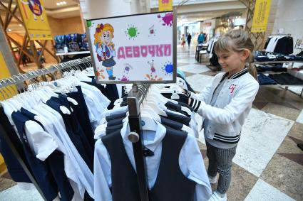 Москва. Девочка выбирает школьную форму  к началу учебного года на школьной ярмарке в `Центральном детском магазине`.