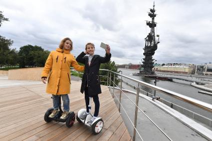 Москва.  Девушки на гироскутерах фотографируются  у  памятника Петру I на  Крымской  набережной.