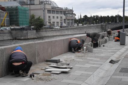 Москва.   Работы по укладке тротуарной  плитки на Якиманской набережной.