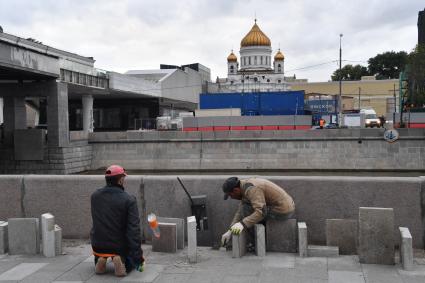 Москва.   Работы по укладке тротуарной  плитки на Якиманской набережной.