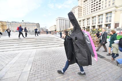 Москва. Мужчина с контрабасом идет по Манежной площади.