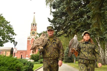 Москва. Кремлевские сокольники Алексей Тюрин с филином Филей   и Юлия Карасева с ястребом Альфа на территории  Кремля.