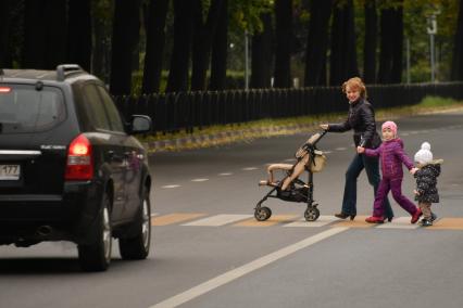 Москва.  Женщина с детьми переходит улицу по пешеходному переходу.