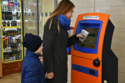 Москва.  Девушка с ребенком оплачивают мобильную связь.