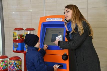 Москва.  Девушка с ребенком оплачивают мобильную связь.