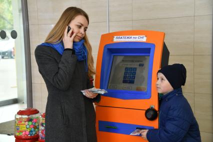 Москва.  Девушка с ребенком оплачивают мобильную связь.