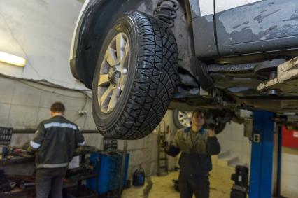 Санкт-Петербург. Автомеханники  производят ремонт колеса автомобиля в автосервисе.