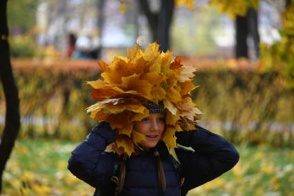 Москва.   Девочка примеряет на голову венок из осенних листьев.