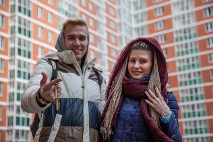 Пермь.  Молодые люди показывают ключи от квартиры в новостройке.