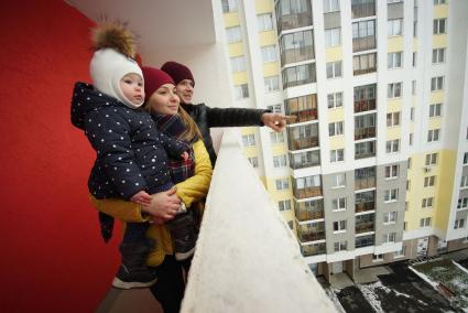 Екатеринбург.  Мужчина и женщина с ребенком  на балконе многоэтажного жилого дома.
