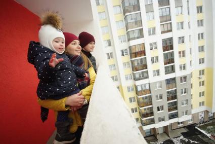 Екатеринбург.  Мужчина и женщина с ребенком  на балконе многоэтажного жилого дома.