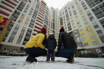 Екатеринбург.  Мужчина и женщина с ребенком смотрят на новостройку.