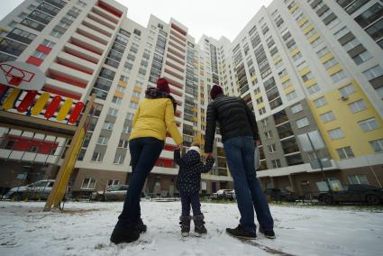 Екатеринбург.  Мужчина и женщина с ребенком смотрят на новостройку.