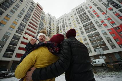 Екатеринбург.  Мужчина и женщина с ребенком смотрят на новостройку.