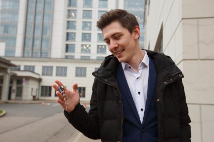 Санкт-Петербург.  Молодой человек держит в руке ключи от квартиры.