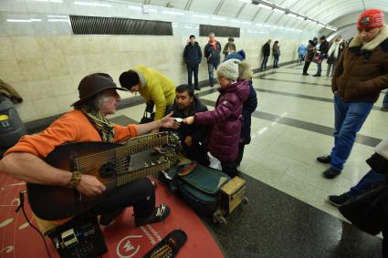 Москва. Девочка дает деньги музыканту в метро.