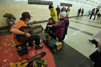 Москва. Девочка дает деньги музыканту в метро.