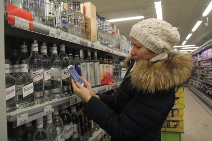 Иркутск.   Покупательница в отделе алкогольной продукции в одном из магазинов.