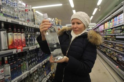 Иркутск.   Покупательница в отделе алкогольной продукции в одном из магазинов.