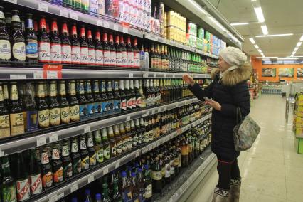 Иркутск.   Покупательница в отделе алкогольной продукции в одном из магазинов.