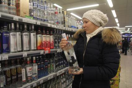 Иркутск.   Покупательница в отделе алкогольной продукции в одном из магазинов.