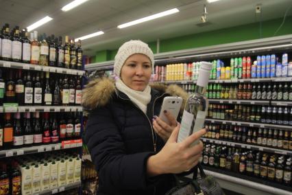 Иркутск. Девушка фотографирует штрихкод на бутылке водки в отделе алкогольной продукции в одном из магазинов.