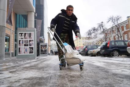 Екатеринбург. Дворник посыпает тротуар антигололедной смесью