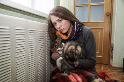 Самара.  Девушка с кроликами   греются у батареи в холодной квартире.
