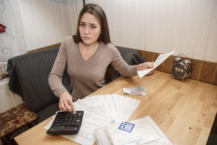 Самара. Девушка изучает квитанции на оплату коммунальных услуг.