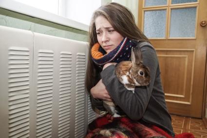 Самара.  Девушка с кроликом  греются у батареи в холодной квартире.