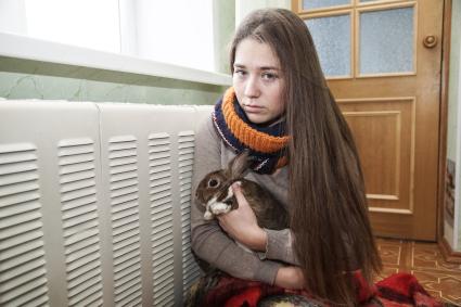 Самара.  Девушка с кроликом   греются у батареи в холодной квартире.