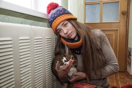Самара.  Девушка с кроликом  греются у батареи в холодной квартире.