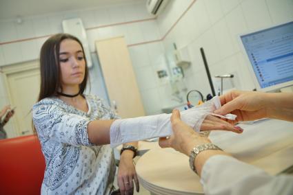 Екатеринбург. Врач-травматолог накладывает фиксирующую повязку на руку девушке в травмпункте