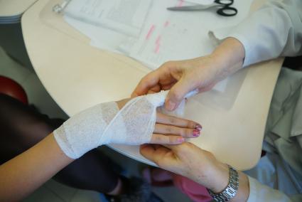 Екатеринбург. Врач-травматолог бинтует руку девушке во время приема в травмпункте