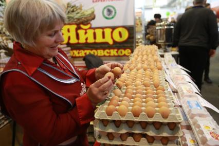 Красноярск.  Продавщица торгует куриными яйцами на ярмарке.