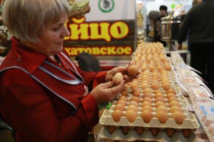 Красноярск.  Продавщица торгует куриными яйцами на ярмарке.