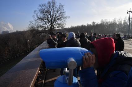 Москва.  Посетители смотрят  в бинокль на смотровой площадке Воробьевых гор.